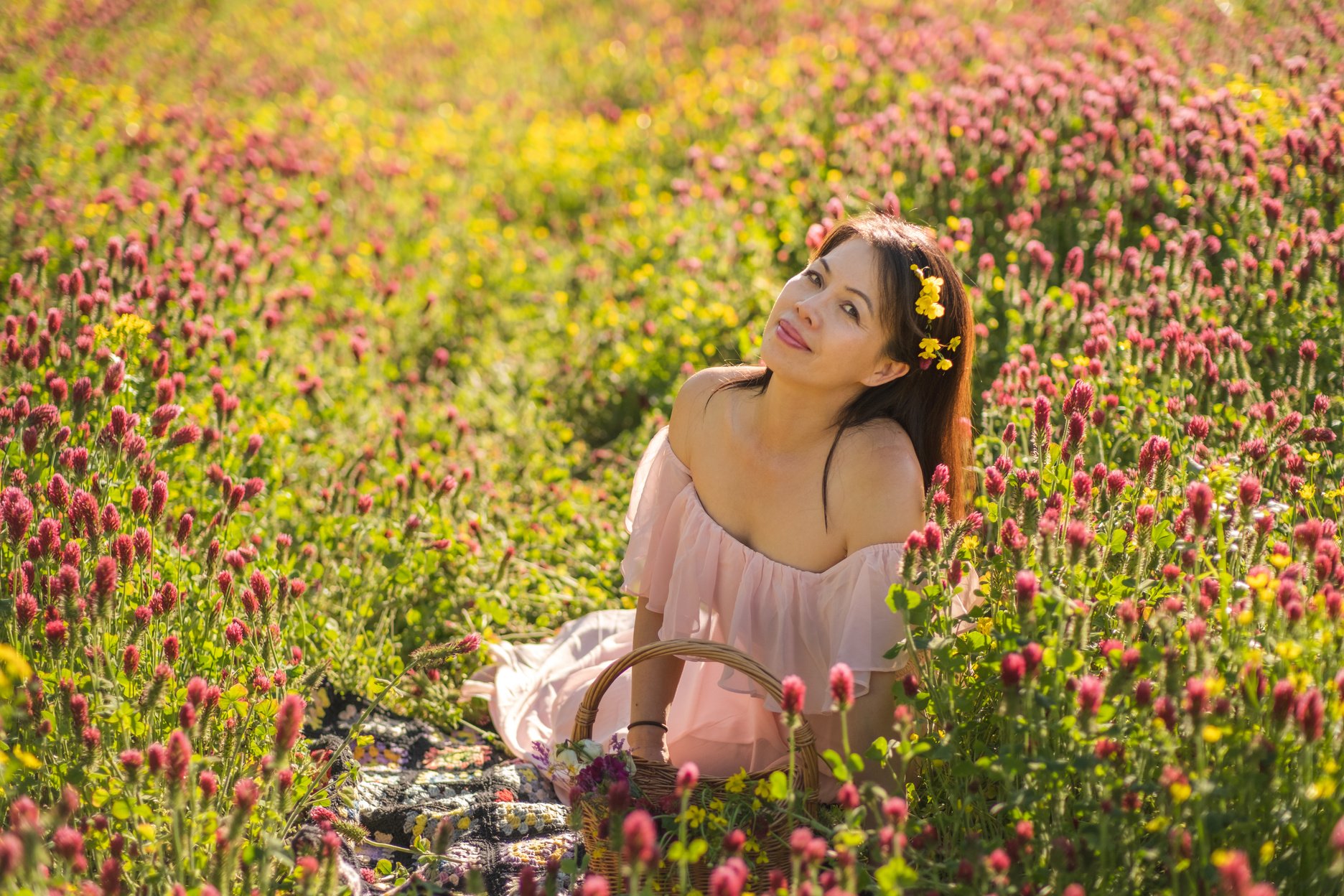 Environmental portrait of beautiful Chinese woman  in Midwestern meadow among  colorful wildflowers in spring